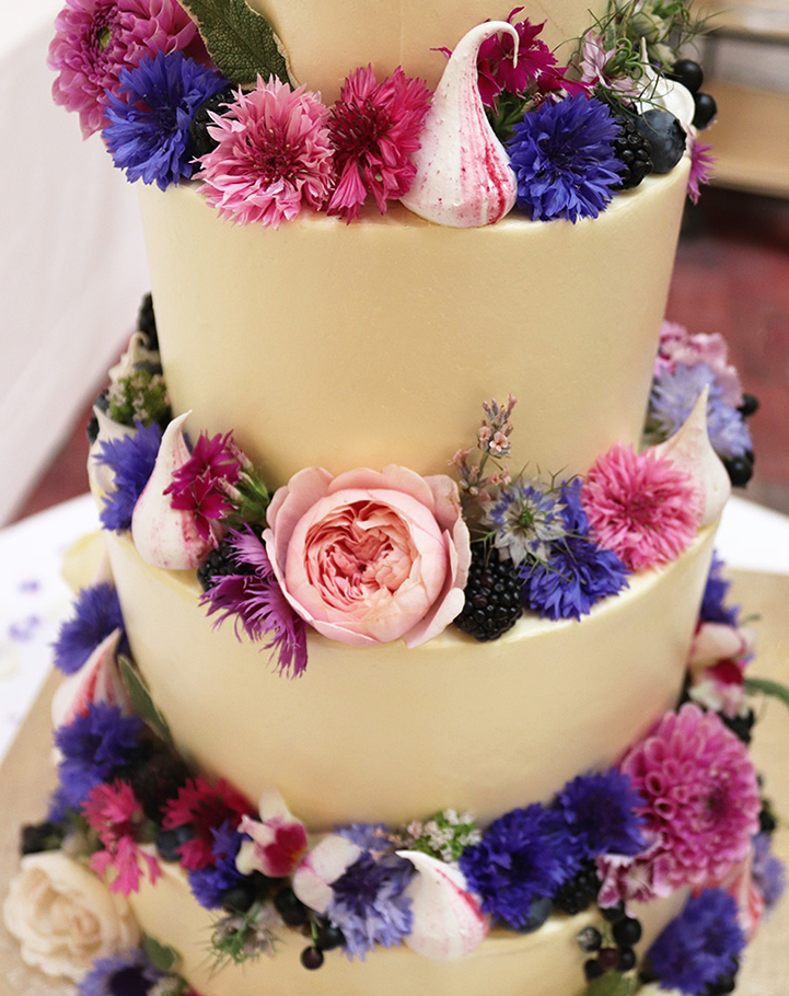 Freefrom wedding cakes in lots of flavours. Here's a 4-tier cake: 3 tiers of White Chocolate, and one of Chocolate & Olive Oil. Frosted with vanilla buttercream, all ingredients organic and gluten-free. Decorated with organic edible flowers. Dairy-free and vegan wedding cakes also available